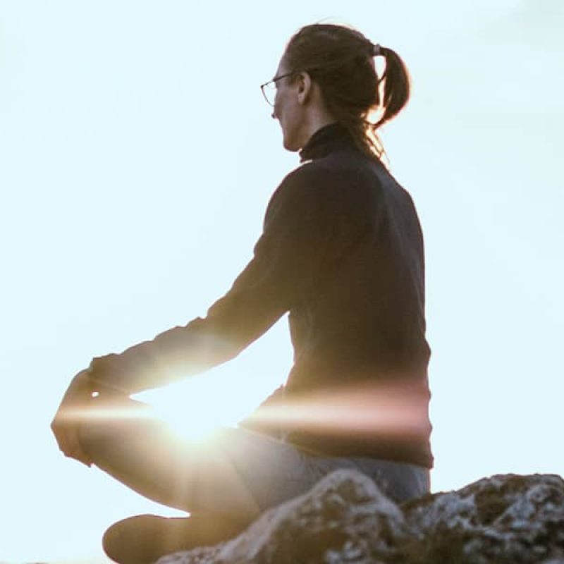 person sitting peacefully on a rock while meditating