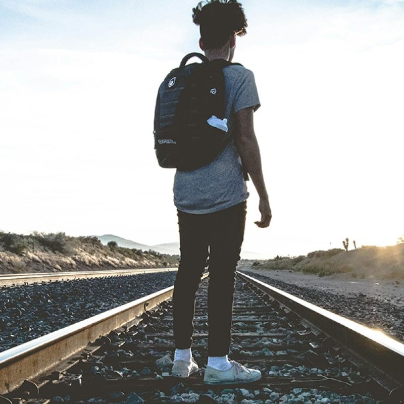 young person walking on train tracks during sunrise