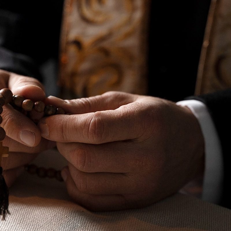 a priest holding a rosary while praying