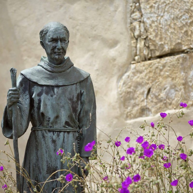 A statue of St. Junipero Serra sits among flowers outside San Carlos Borromeo de Carmelo Mission in Carmel, Calif. The Spanish missionary was canonized by Pope Francis last year under the title of "apostle of California." St. Junipero's feast is July 1. (CNS photo/Nancy Wiechec)