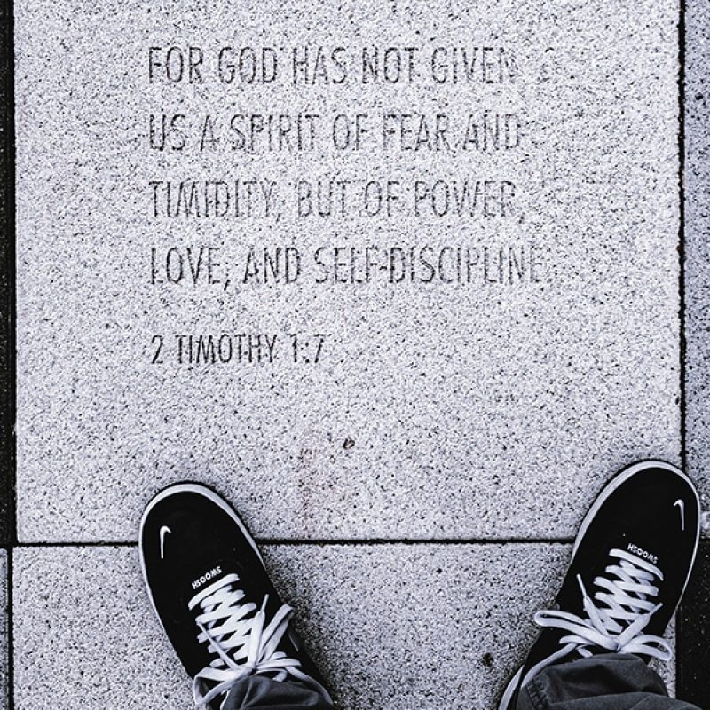 shoes and feet next to word scripture set in stone.