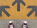 feet in sneakers in front of three arrows