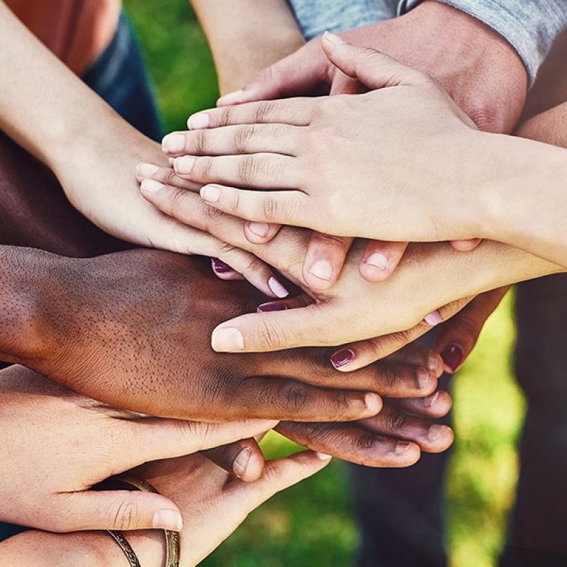 group of people stacking their hands as a sign of solidarity and teamwork