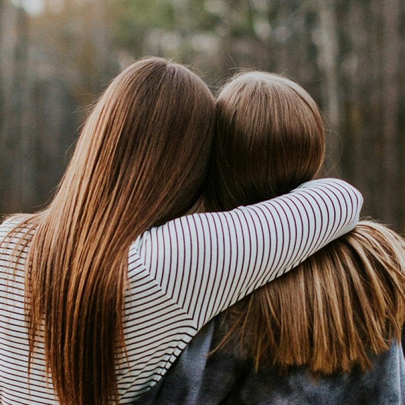 Two women friends embracing, one comforting the other.