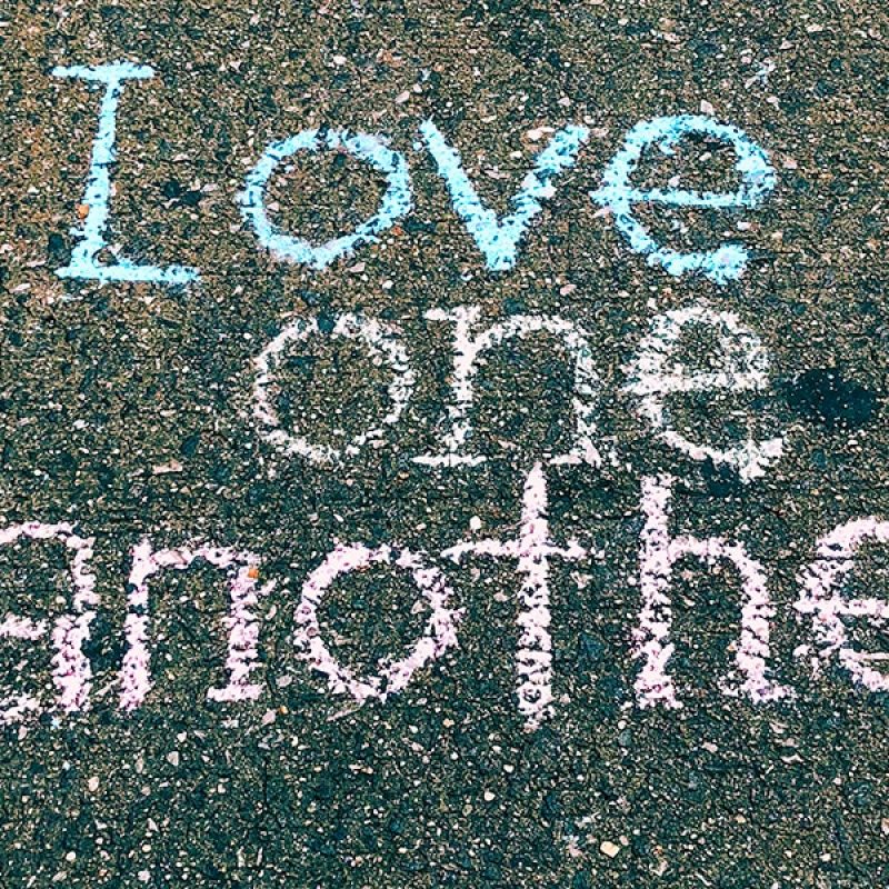 surrender to love; "love one another" written in chalk on the sidewalk; Jon Tyson/Unsplash