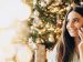 the celebration of christmas; woman on her cellphone in front of a Christmas tree.