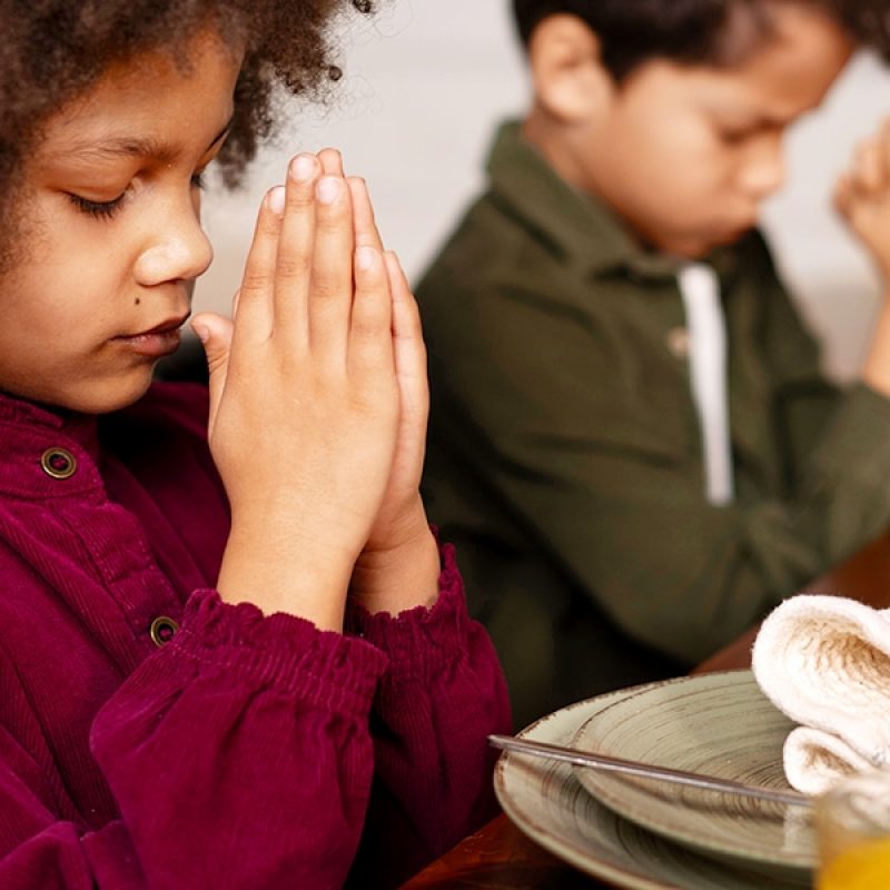 Two kids praying with folded hands before meal