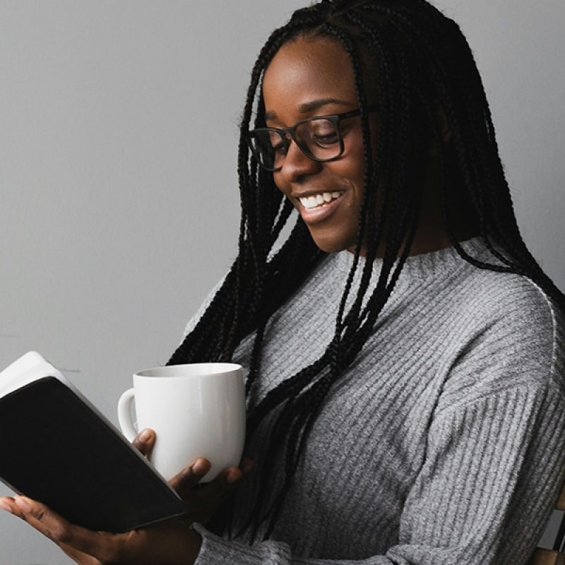 Young woman enjoys reading a book while drinking coffee