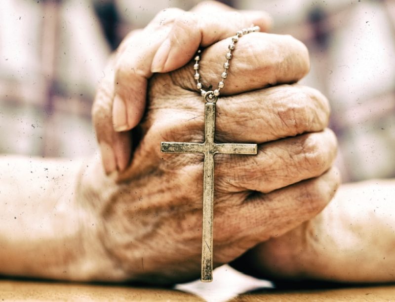 Woman holding a cross in prayer