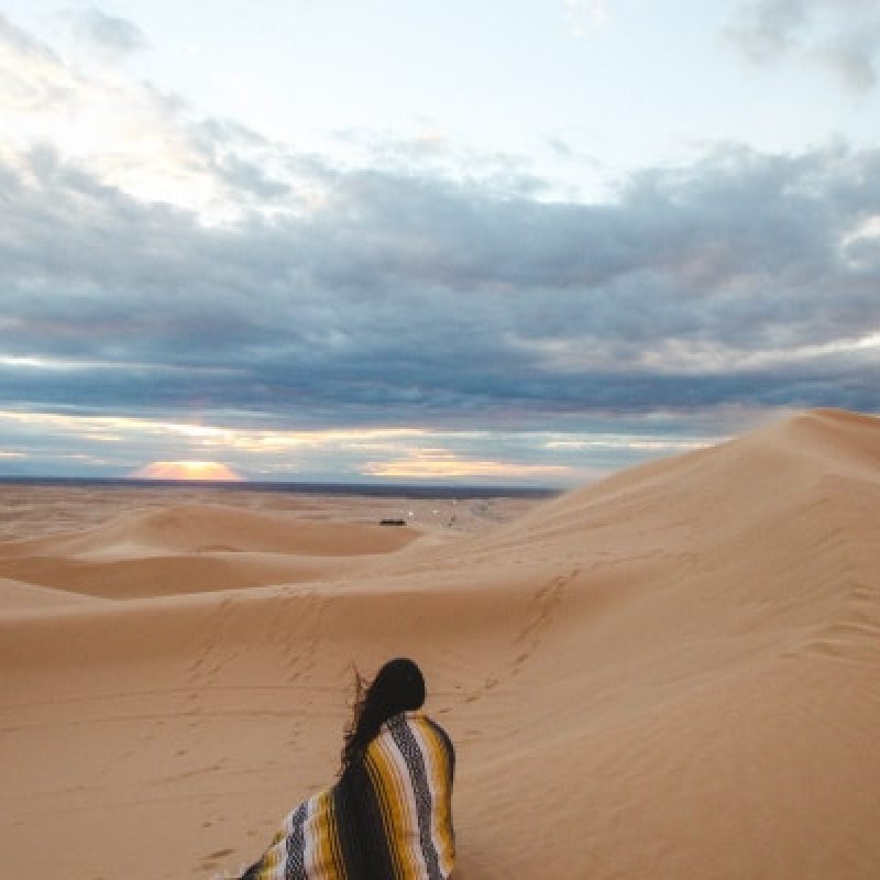 woman-sitting-alone-on-a-sand-dune
