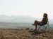 woman sitting in a chair outside with mountains in the background.
