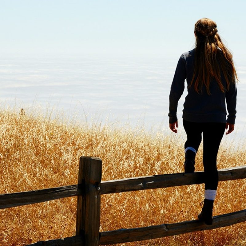 woman climbing over wood fence.
