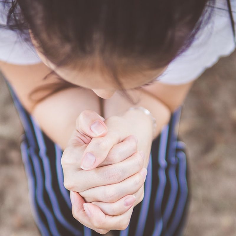 woman with folded hands praying.