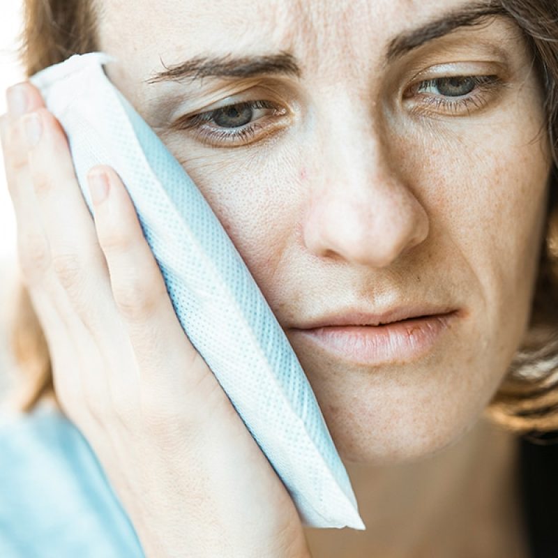 woman holding a icepack agains her painful head.