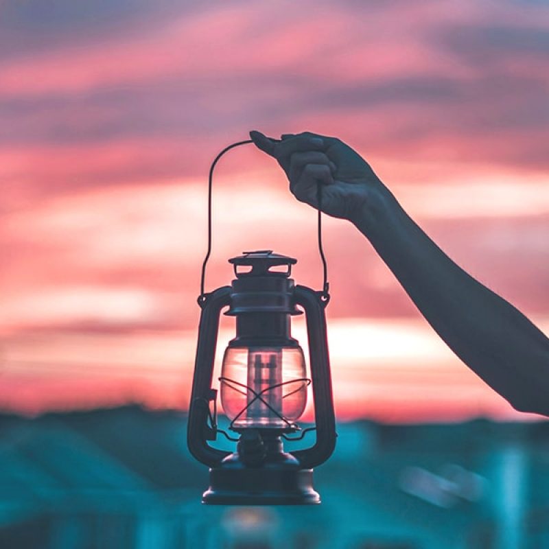 woman holding a lantern at sunset