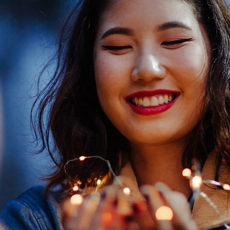 woman praying while holding lights in her hands