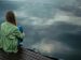 Woman sitting alone on a pier.