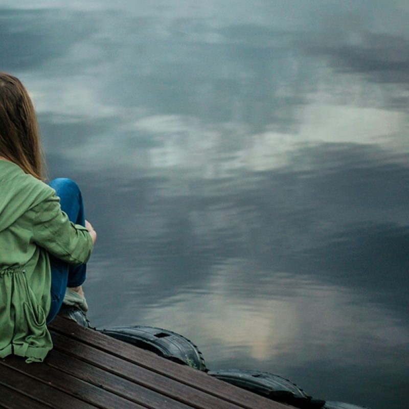 Woman sitting alone on a pier.