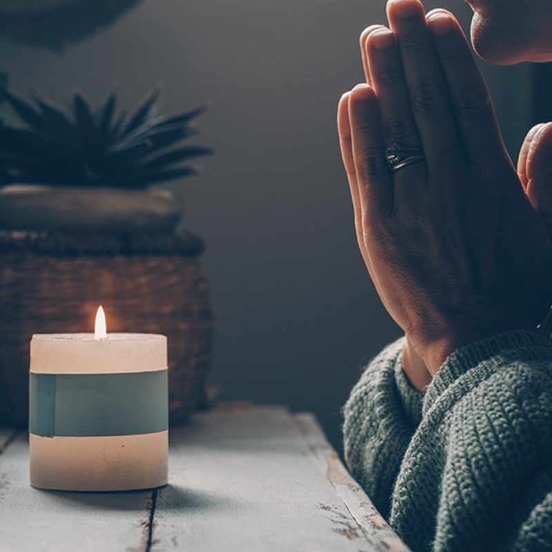 woman_praying_candle woman praying with folded hands in front of a candle