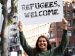 woman holding a sign welcoming refugees.