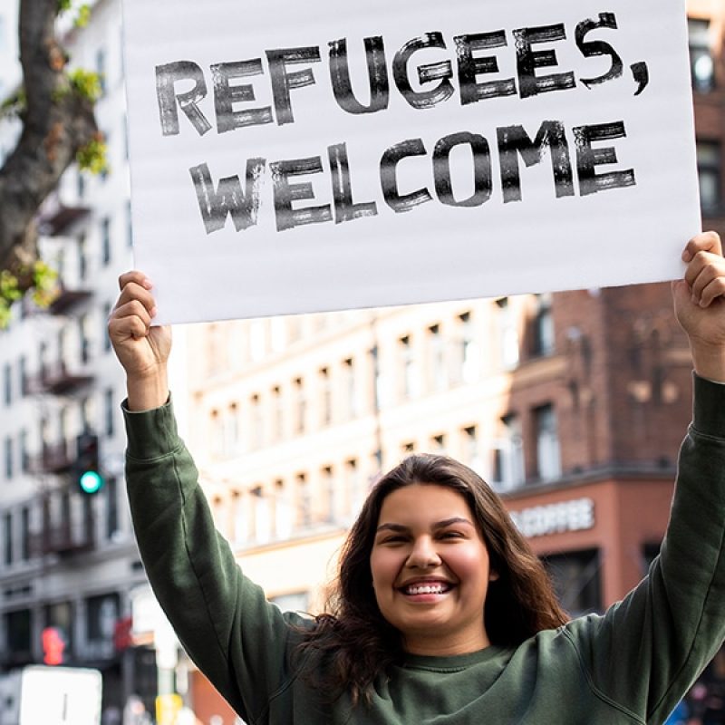 woman holding a sign welcoming refugees.