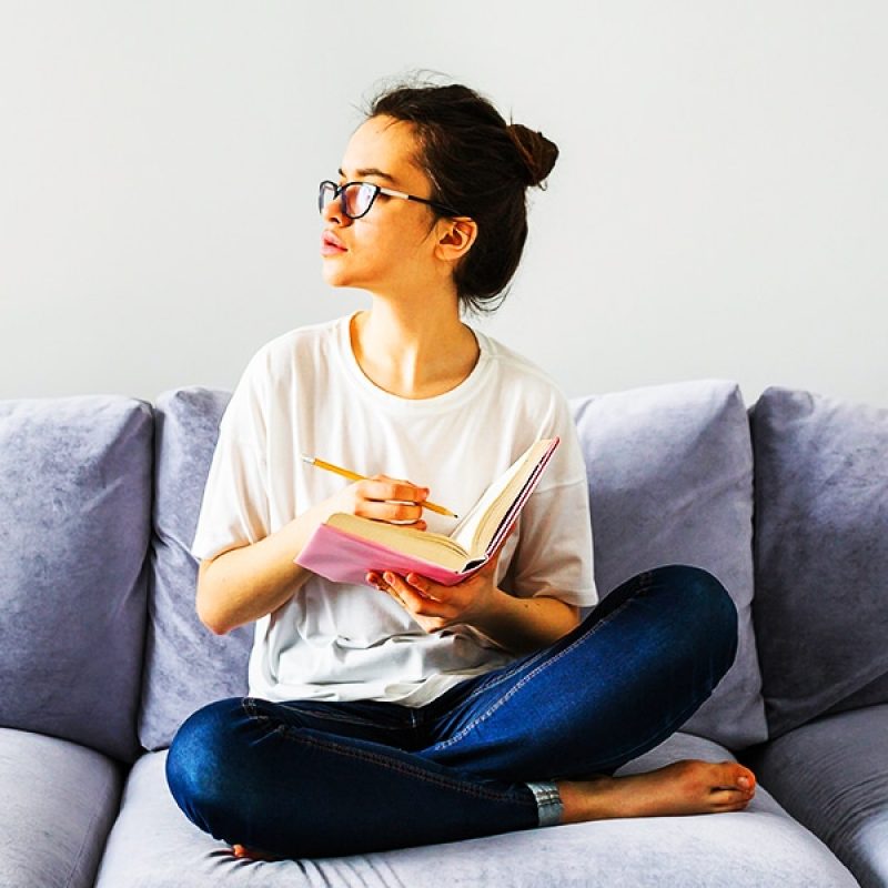 woman sitting on a couch reading a book in a minimalist room.