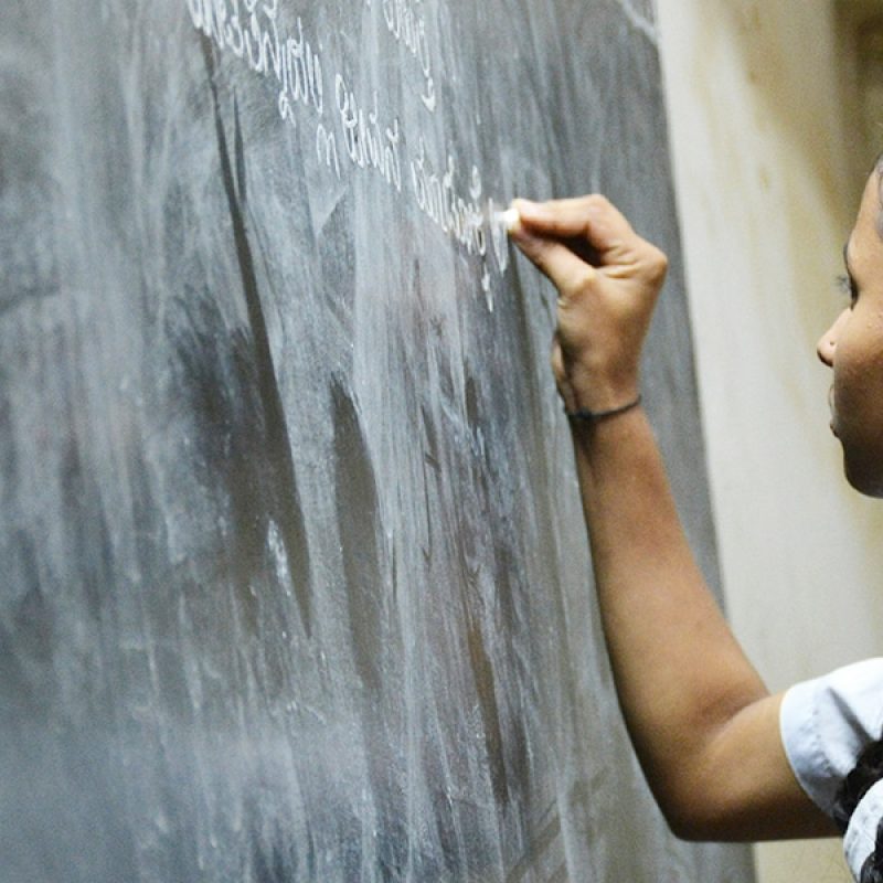 woman teacher writing on chalk board