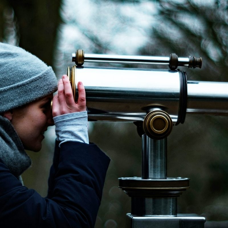 Woman looking beyond through telescope