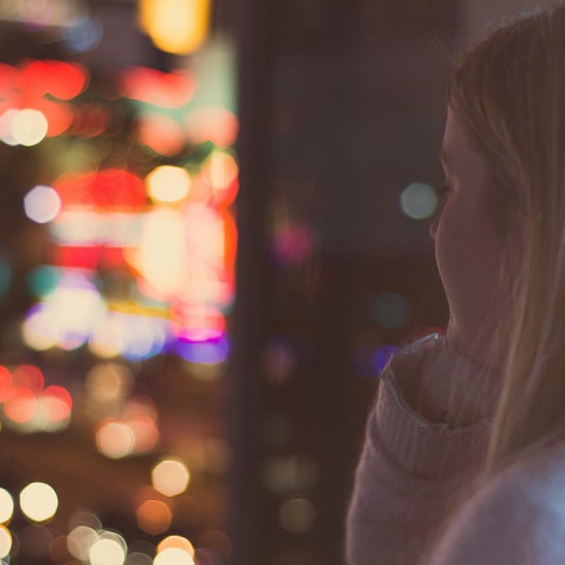 woman looking at lights outside a window