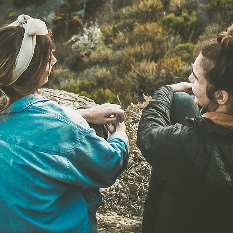 two women sitting on a hill, having a conversation